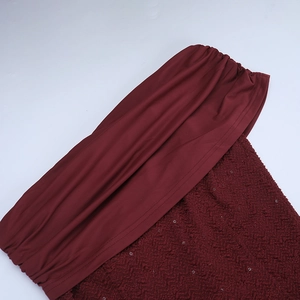 Détail de la couture du tissu à paillettes rouge vin sur une robe de soirée dos nu