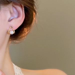 Close-up of elegant gold teardrop earrings with white pearl inlay on model