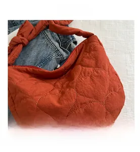 Detail of burnt orange quilted tote bag with heart pattern and decorative knotted strap