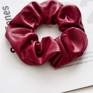 Macro shot of dark red PU leather scrunchie showing detailed textures and pleats