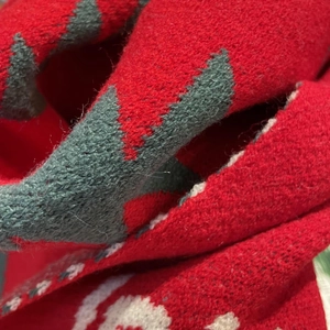 Macro detail of Christmas snowman knit scarf with green tree patterns and white snowflakes
