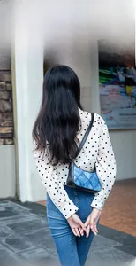 Rear view of a model wearing the blue quilted denim shoulder bag with black leather straps