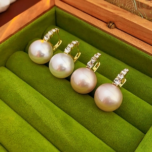 Macro detail of luxury pearl earrings with diamonds on green velvet tray