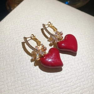 Detailed macro view of red heart drop earrings with gold finish and sparkling zircon accents