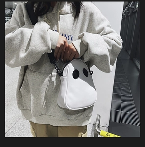 Street style shot of a white ghost PU crossbody bag with black adjustable strap for women