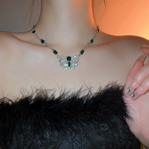 Gros plan du collier papillon en émeraude avec diamants argentés sur le décolleté