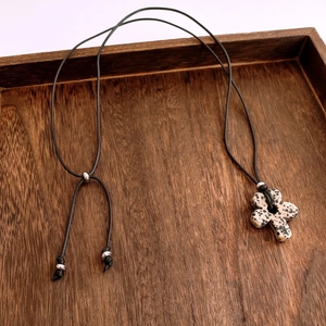 Detail of flower-shaped tiger eye stone pendant on adjustable black cord over wood surface