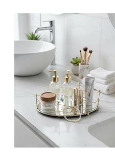 Close-up of a gold mirrored tray with cosmetics and pearls on a marble vanity