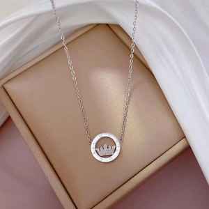 Close-up of a silver crown pendant with Lucky engraving on a gold luxury jewelry box