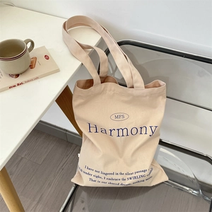 Detailed shot of beige canvas tote bag with MFS Harmony text print on a chair