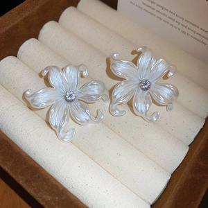 Close-up of pearl white acrylic flower earring with central sparkling zircon stone