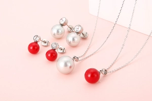 Detail of silver pearl necklace set and red bead jewelry set on pink background