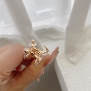 Detailed close-up of a golden flower hair claw clip with translucent petal elements