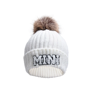 Close-up of white ribbed knit beanie with MINI embroidery and large faux fur pom-pom