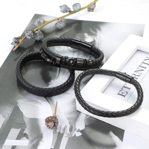 Detail of three black braided leather bracelets with matte metal clasps on a white base
