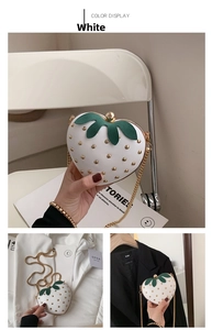 Detail of white strawberry heart bag with green leaves and golden rivets on chain