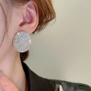 Macro shot of large round pavé diamond earrings with gold finish and sparkling crystals
