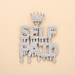 Macro detail of silver-toned Self Paid iced-out pendant with crown design and crystals