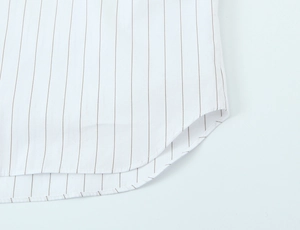 Macro detail of curved hem and precise stitching on white striped commute shirt