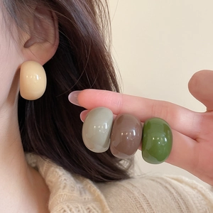 Close-up of semi-spherical acrylic C-shaped earrings in various Morandi colors