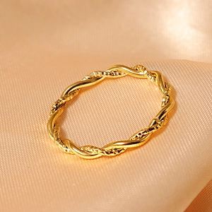 Elegant gold twisted rope stainless steel ring on silk background for women