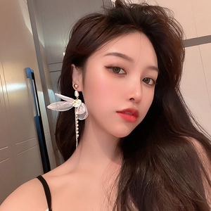 Detailed view of long tulle bow earrings with gold chains and delicate faux pearls