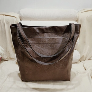 Détail du sac cabas marron vintage montrant la poche avant et le cuir ciré souple