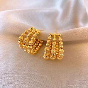 Vue détaillée des boucles d'oreilles dorées à trois rangées de perles sur de la soie