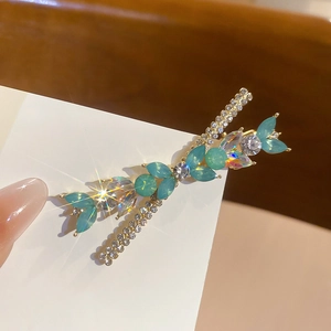 Vue macro détaillée d'une barrette dorée ornée de gemmes bleu sarcelle et strass