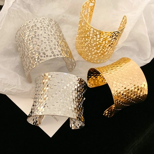 Detailed close-up of woven mesh pattern and chunky gold and silver hollow arm cuffs