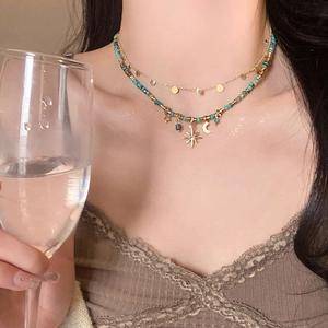 Detail of layered gold star and moon necklace with turquoise beads on female model
