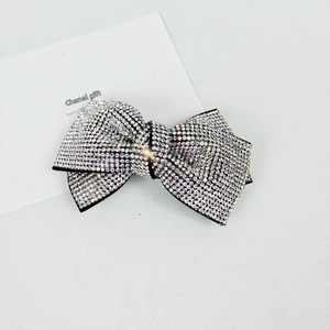Detailed view of elegant black bow hair clip featuring sparkling clear micro rhinestones