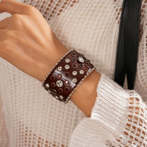 Détail macro du bracelet manchette en cuir marron avec strass et bordures en perles
