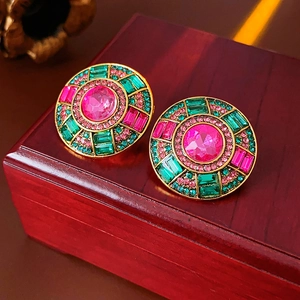 Close-up of vintage round earrings with pink crystal centers and green emerald cut stones