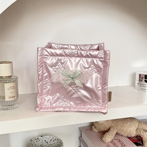 Detail of pink quilted storage basket with embossed bow pattern and lace ribbon decoration