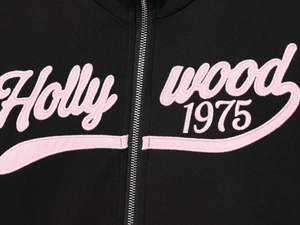 Detail of metal zipper and pink Hollywood 1975 embroidery on black hoodie fabric