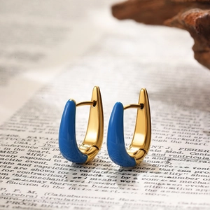 Macro shot of gold U-shaped earrings with blue enamel detail on vintage background