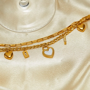 Detail of layered gold stainless steel necklace with heart pendants on champagne silk
