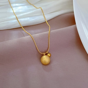 Detail of gold titanium steel necklace featuring matte and polished spheres on snake chain