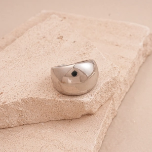 Detailed close-up of a silver dome ring with polished metallic finish on stone tiles