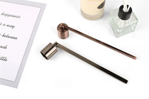 Close-up of bronze and gunmetal candle snuffers with bells on a white minimalist table
