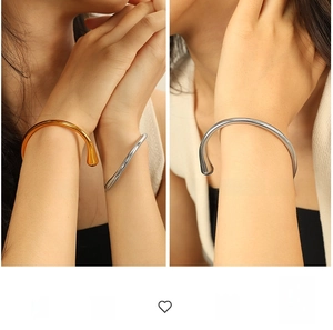 Dettaglio ravvicinato di bracciali aperti minimalisti dorati e argentati a goccia