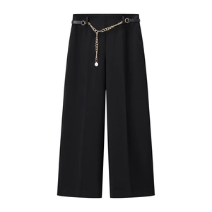 Dettaglio dei pantaloni neri a vita alta e gamba larga con cintura a catena dorata elegante