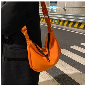 Close-up of bright orange nylon crescent bag with adjustable black shoulder strap