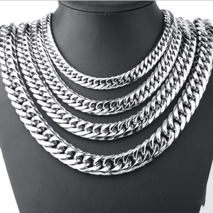 Macro detail of multi-layered silver stainless steel Cuban link necklaces on a black bust