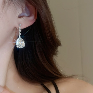 Close-up of sparkling waterdrop tassel earrings with crystal pavé on a model