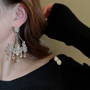 Boucles d'oreilles pendantes fleurs en argent avec cristaux sur un modèle féminin