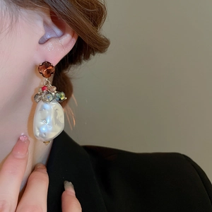 Detailed close-up of Baroque pearl earrings with crystal beads and gemstone on model