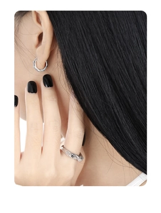Detail shot of silver geometric hexagonal earrings and irregular textured ring on model