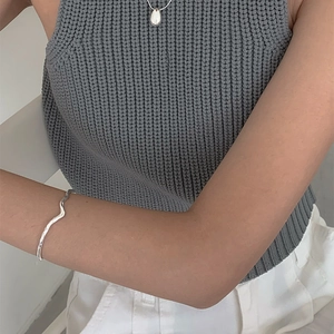 Minimalist silver wavy bangle and teardrop pendant necklace set on a female model